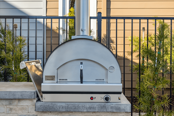 A wood-fired oven is placed on a patio.